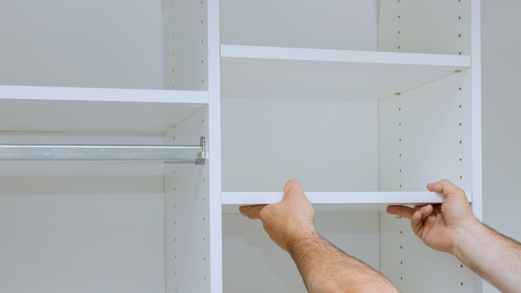 A man is holding a piece of plywood in a closet